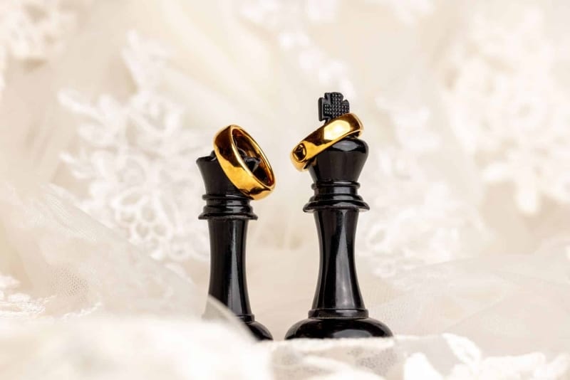 2-wedding-rings-sitting-on-top-of-2-pieces-of-chess