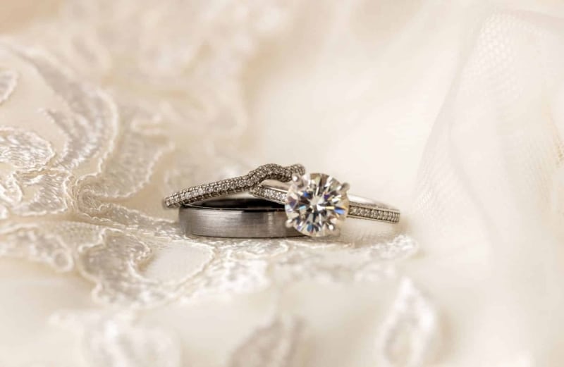 3-wedding-rings-sitting-on-top-of-white-dress