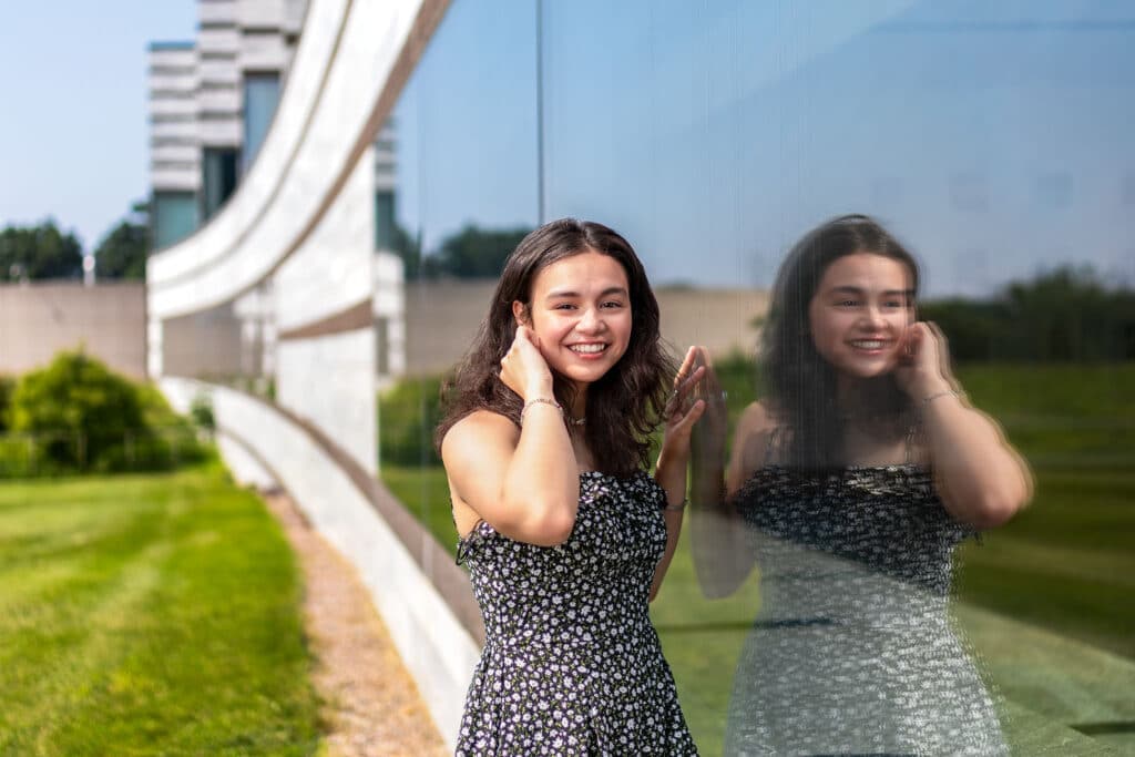 Gillian posing next to a window with her reflection in it