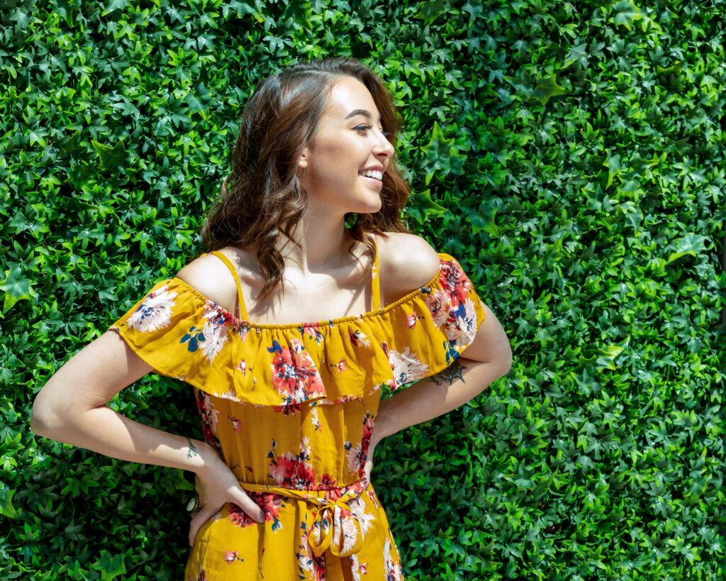 Senior picture of Sophia next to a greenery wall